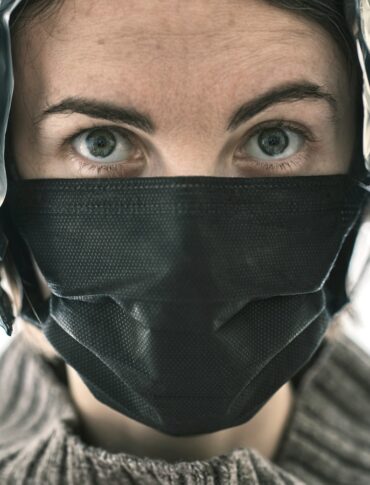 a woman wearing a black mask with feathers on it