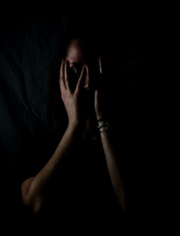 woman holding her face in dark room