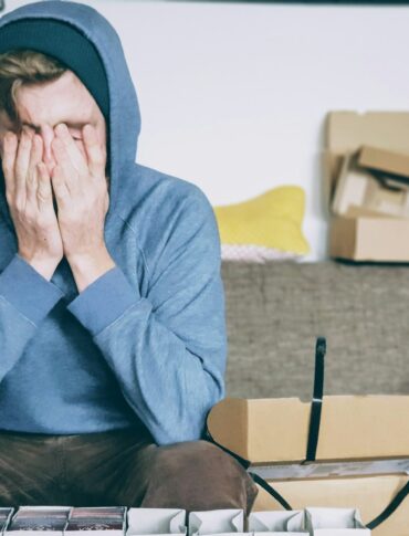 man covering face with both hands while sitting on bench